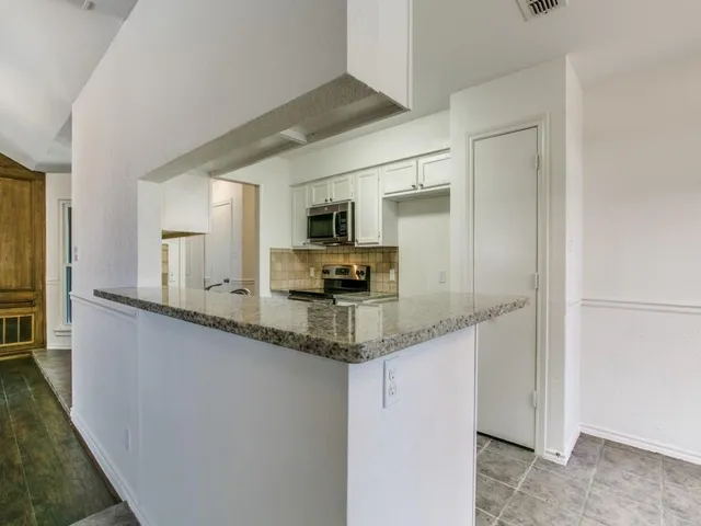 a kitchen with granite countertop a sink and a refrigerator
