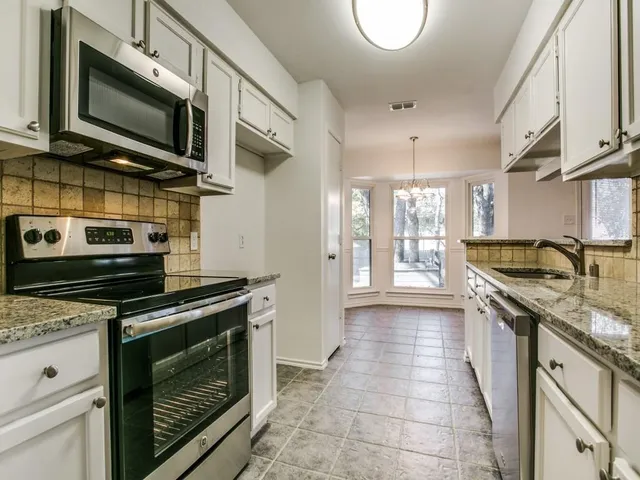 a kitchen with stainless steel appliances granite countertop a stove top oven microwave and cabinets