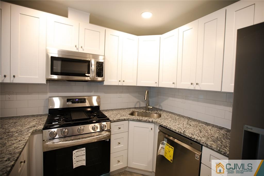 3507 Hana Road Edison, NJ 08817 - Photo 5 of 18 a kitchen with granite countertop a stove top oven microwave and cabinets