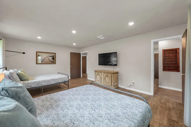a spacious bedroom with a bed and a flat screen tv