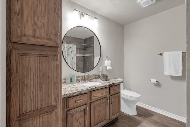 a bathroom with a granite countertop toilet a sink and a mirror