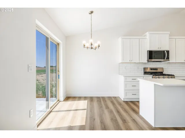 a open kitchen with kitchen island a stove a sink and white cabinets