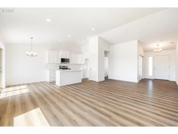 a view of kitchen and empty room with wooden floor