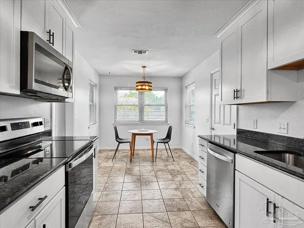 a kitchen with granite countertop a stove a sink and a microwave