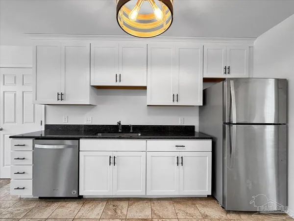 a kitchen with granite countertop white cabinets white stainless steel appliances and a refrigerator