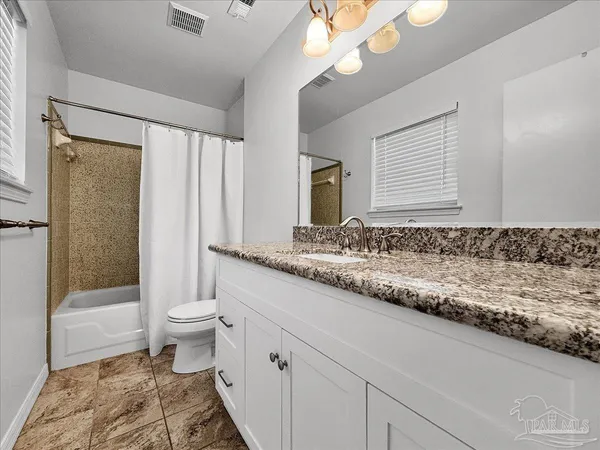 a bathroom with a granite countertop sink a toilet a mirror and shower