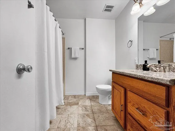 a bathroom with a granite countertop sink a toilet a mirror and shower