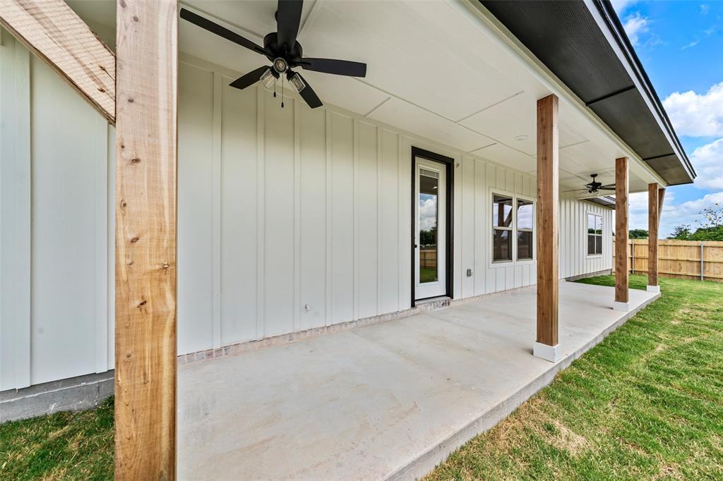 138 Dana Pt Road Lorena, TX 76655 - Photo 21 of 24 Expansive concrete patio with wood-finish support columns, board-and-batten siding, black ceiling fans, and a glass-paneled exterior door
