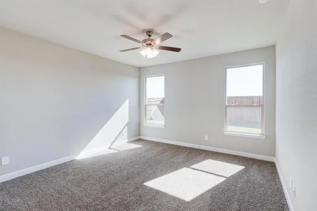a view of an empty room with window and chandelier fan