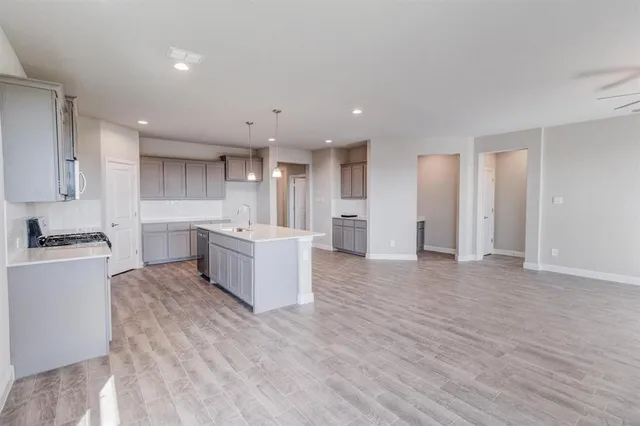 a large kitchen with a large counter top a sink stainless steel appliances and cabinets