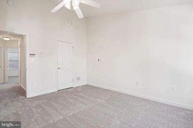 an empty room with a chandelier fan and closet