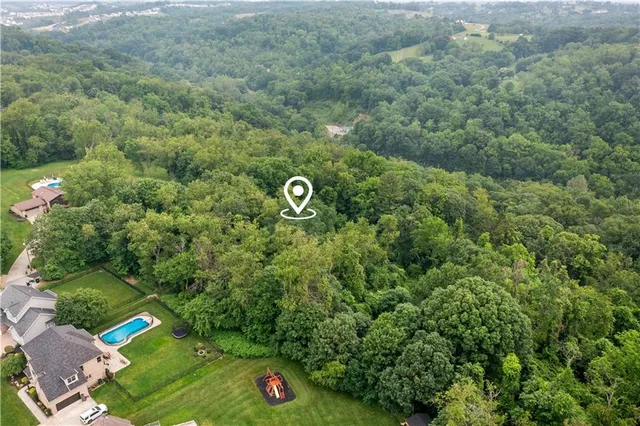 an aerial view of residential house with outdoor space and trees all around