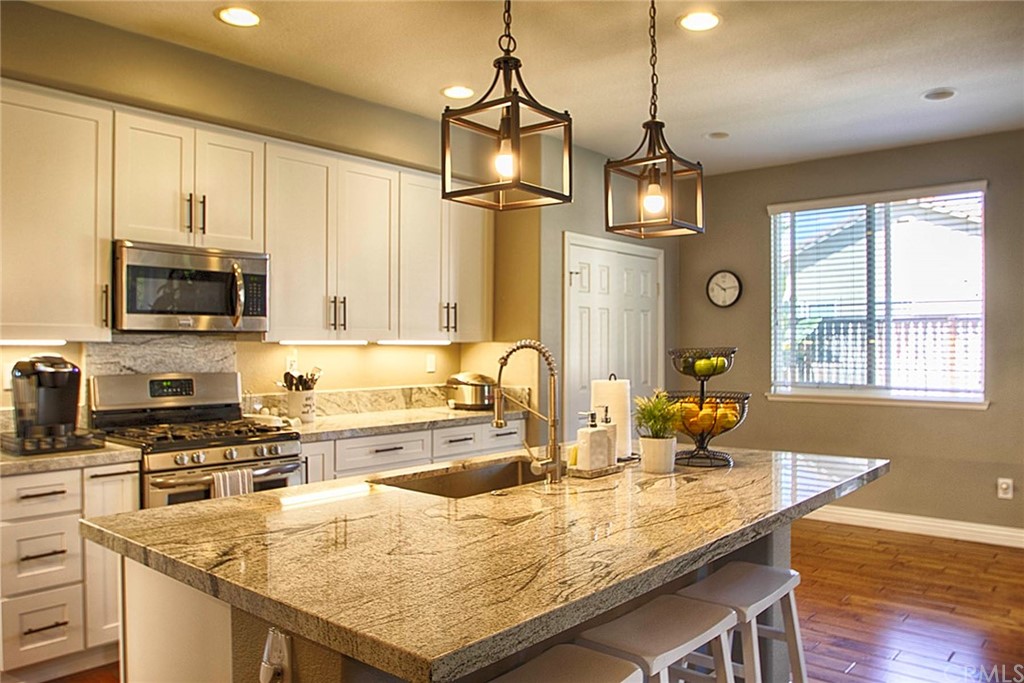 a kitchen with kitchen island granite countertop a sink a counter top space appliances and cabinets
