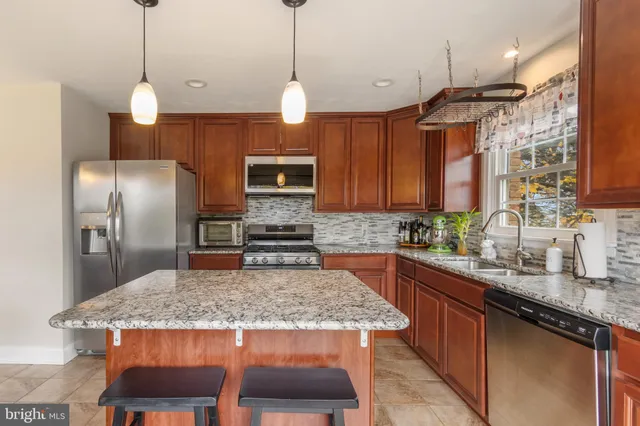 a kitchen with kitchen island granite countertop a sink a center island and stainless steel appliances
