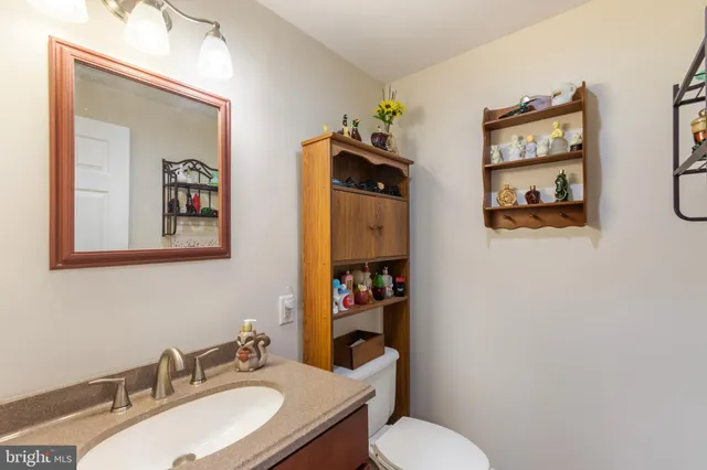 a bathroom with a granite countertop toilet a sink and mirror