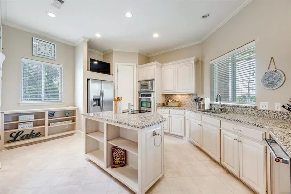 a large white kitchen with stainless steel appliances granite countertop a stove and a sink