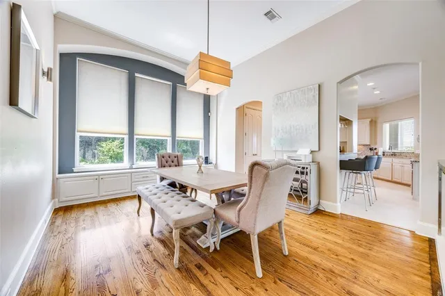 a dining room with wooden floor a chandelier a glass table and chairs