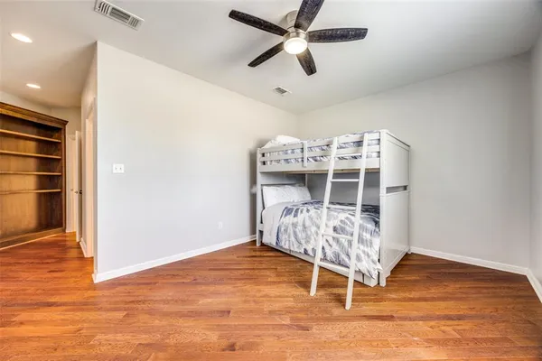 an empty room with wooden floor and ceiling fan