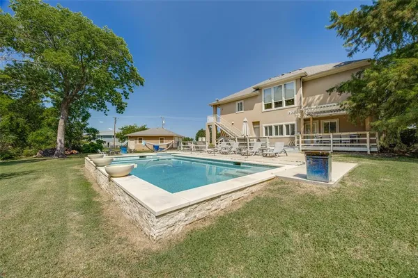 a view of a swimming pool with lawn chairs and plants