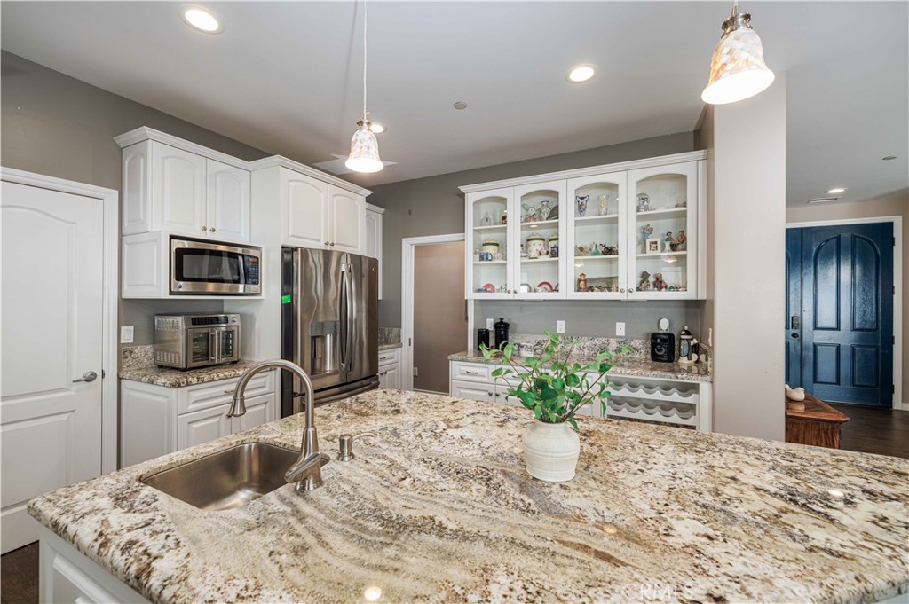 a kitchen with stainless steel appliances kitchen island granite countertop a refrigerator and a sink