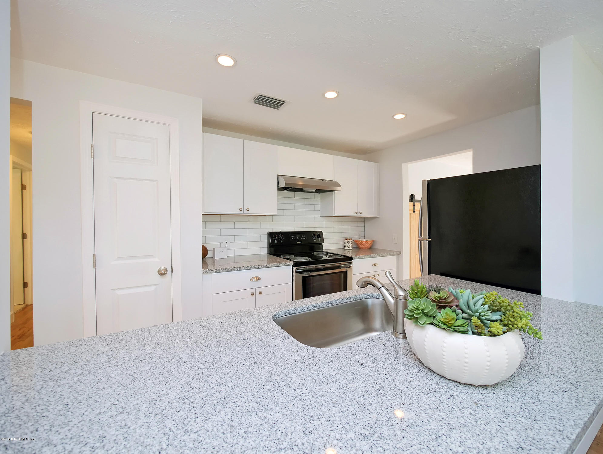411 Skate Road Atlantic Beach, FL 32233 - Photo 7 of 26 a kitchen with a stove and white cabinets