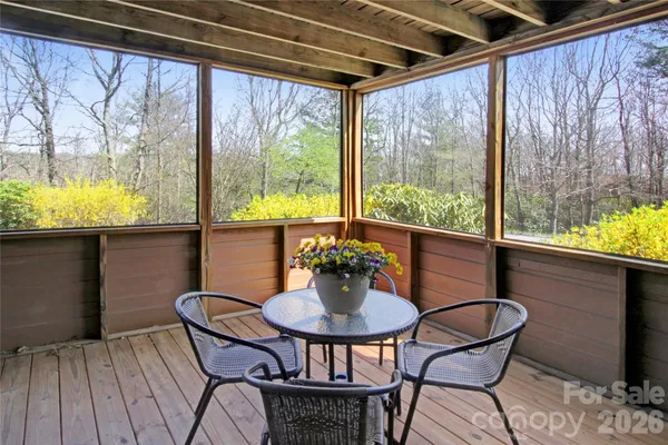 a view of a porch with wooden floor and roof with a garden view