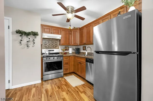 a kitchen with stainless steel appliances a refrigerator a sink a stove and white cabinets