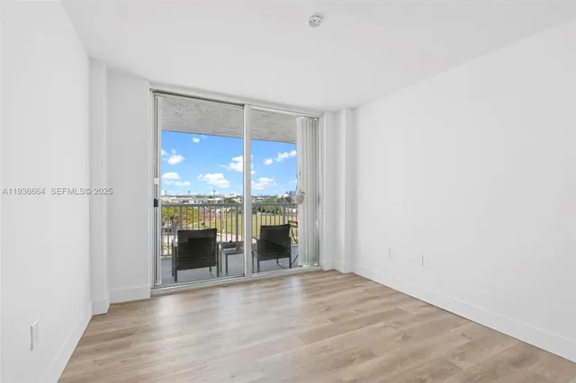 an empty room with wooden floor and a large window