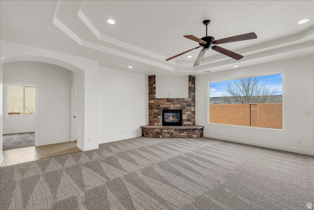 691 Rainier Drive St. George, UT 84770 - Photo 4 of 24 Unfurnished living room featuring light colored carpet, arched walkways, recessed lighting, a stone fireplace, and ceiling fan