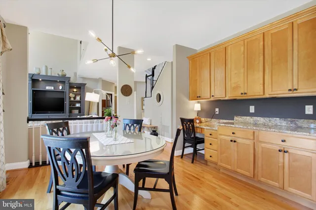 a kitchen with stainless steel appliances granite countertop a kitchen island hardwood floor sink stove dining table and chairs