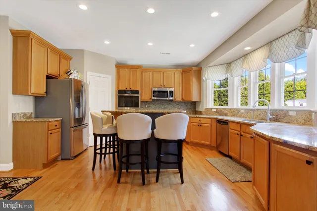 a kitchen with stainless steel appliances granite countertop a kitchen island a table and chairs in it