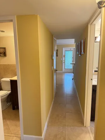 a view of a hallway with wooden floor and a bathroom