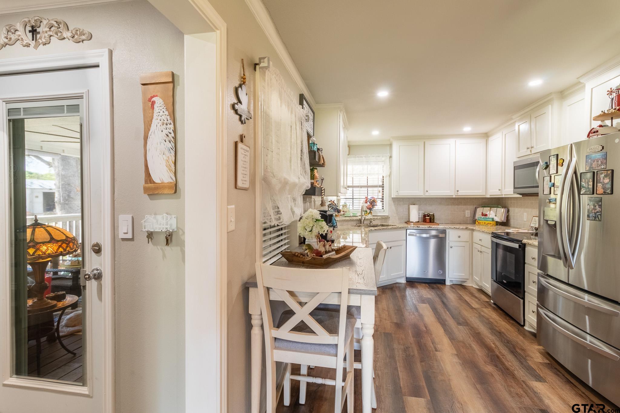 15540 State Highway 31 West Tyler, TX 75709 - Photo 12 of 37 a view of a kitchen with a refrigerator a sink and dishwasher a stove top oven with wooden floor