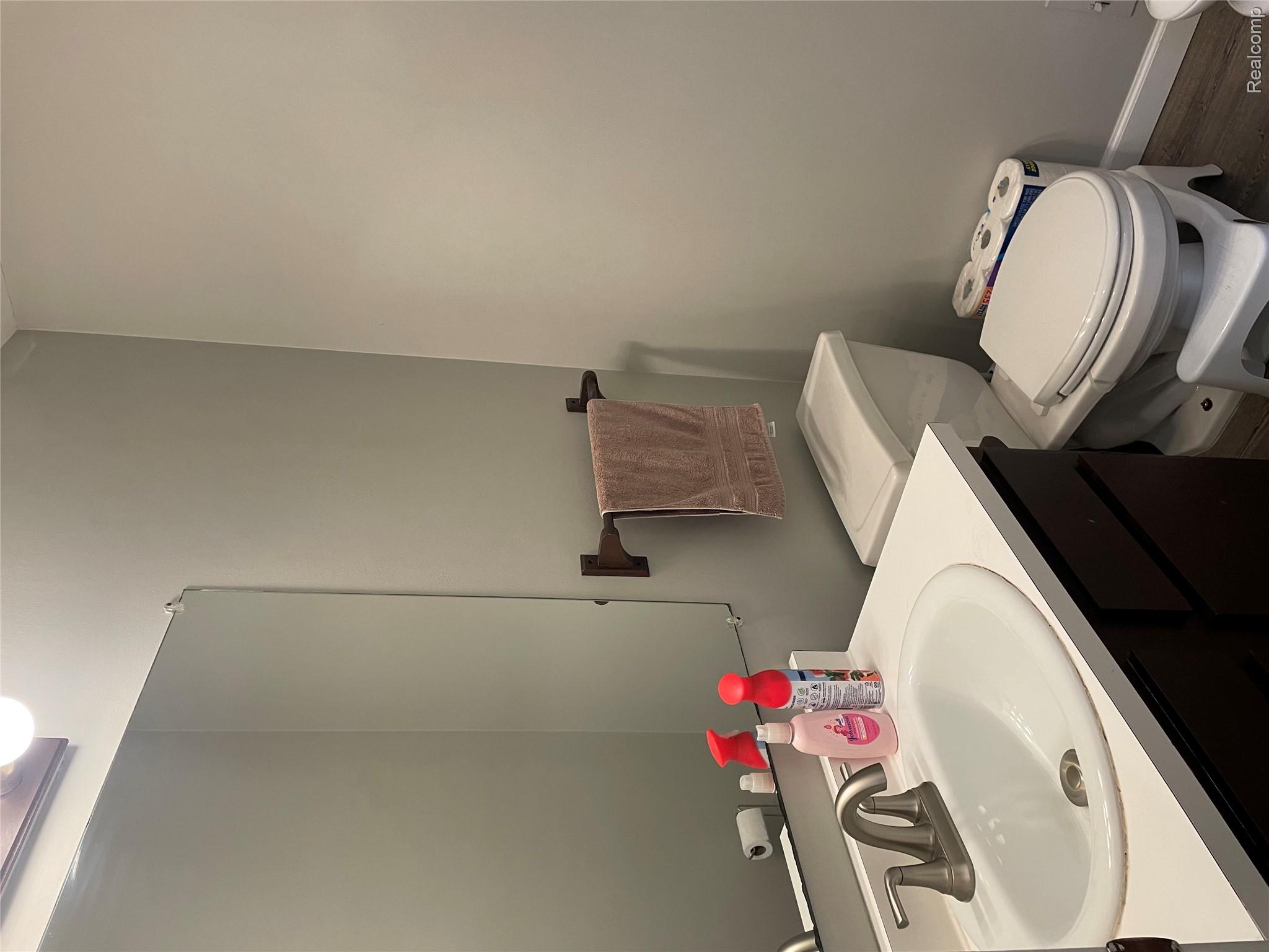 265 Reno Street Lake Orion, MI 48362 - Photo 7 of 11 Bathroom featuring a white ceramic oval sink, brushed nickel faucet, a dark wood-finish vanity with countertop, and wood-look flooring