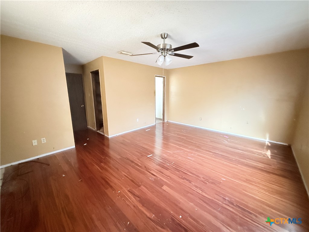 4700 Old Howard Road Temple, TX 76504 - Photo 14 of 33 an empty room with wooden floor a ceiling fan and windows