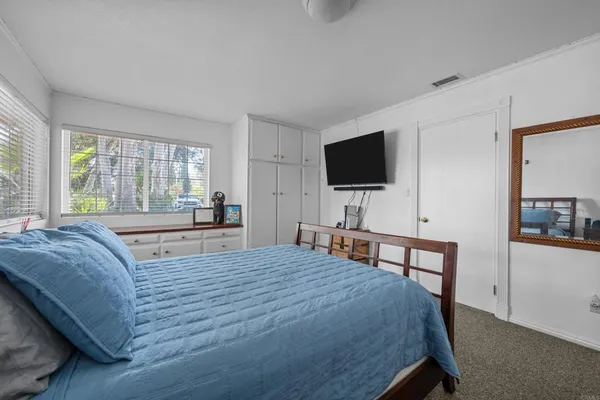 a bedroom with a bed a large window and a flat screen television