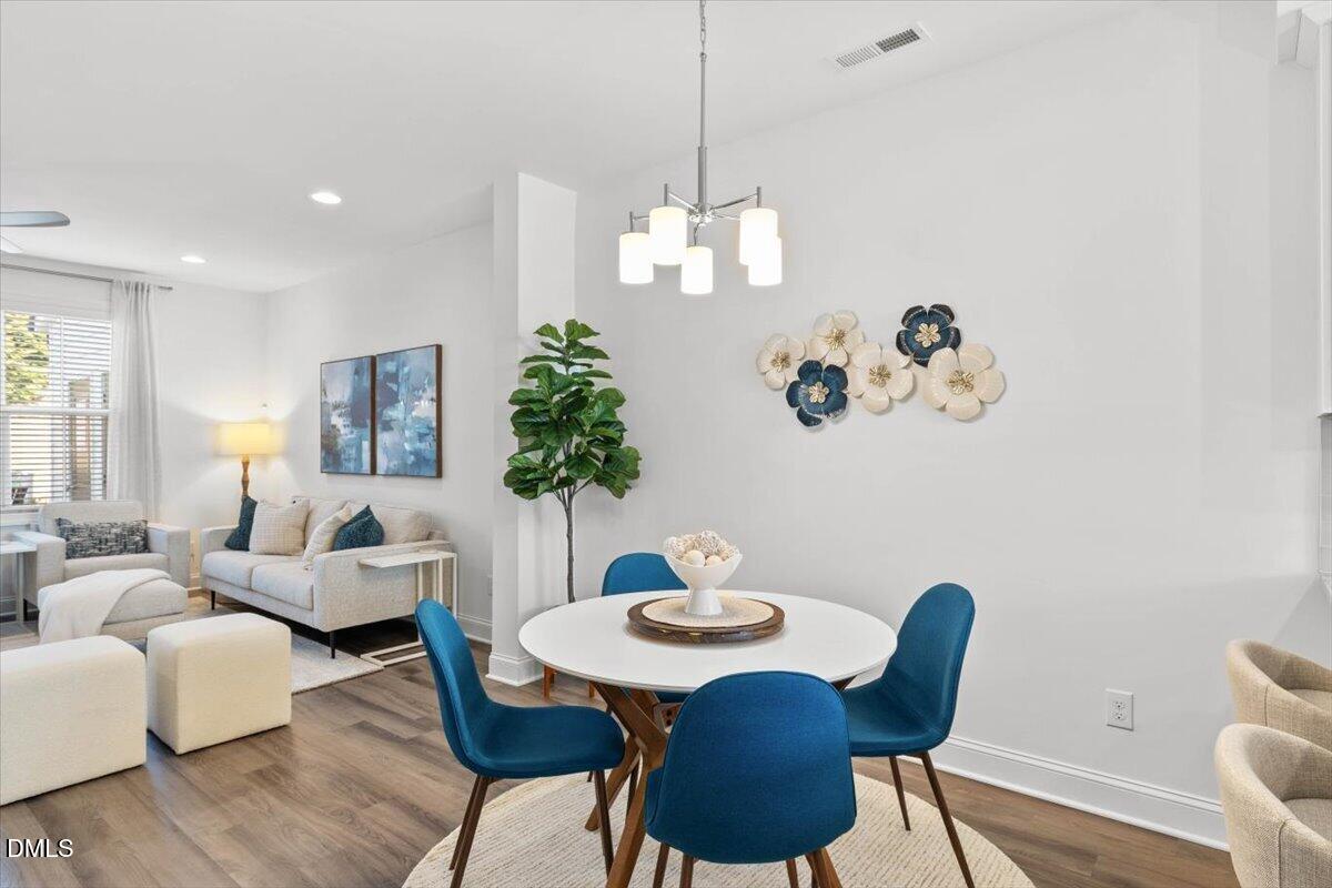 6810 Milligan Way, Unit 103 Raleigh, NC 27613 - Photo 13 of 37 a view of a dining room with furniture wooden floor and a chandelier