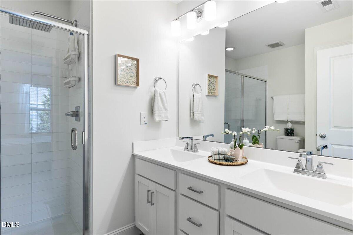 6810 Milligan Way, Unit 103 Raleigh, NC 27613 - Photo 25 of 37 a bathroom with double sink and a mirror
