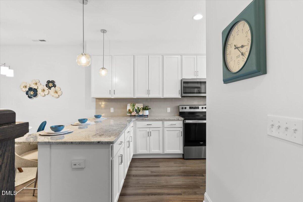 6810 Milligan Way, Unit 103 Raleigh, NC 27613 - Photo 4 of 37 a kitchen with stainless steel appliances granite countertop a sink a stove and a microwave