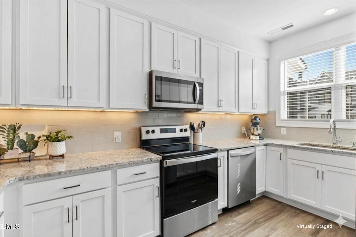 6810 Milligan Way, Unit 103 Raleigh, NC 27613 - Photo 7 of 37 a kitchen with granite countertop white cabinets sink and stainless steel appliances