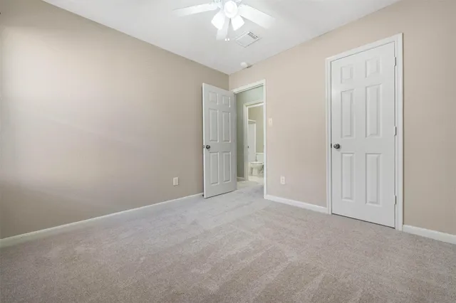 an empty room with a chandelier fan and closet area