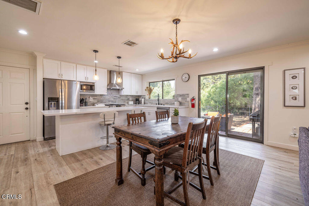 851 Pine Knot Avenue Big Bear Lake, CA 92315 - Photo 10 of 27 a view of a dining room and livingroom with furniture wooden floor a rug a chandelier