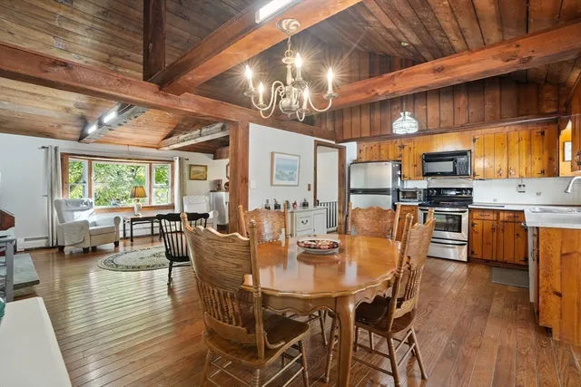 a dining room with wooden floor a chandelier a glass table and chairs