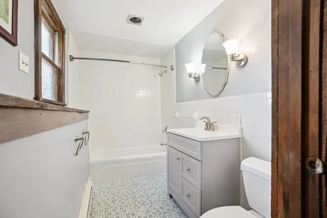 a bathroom with a sink a toilet a mirror and shower