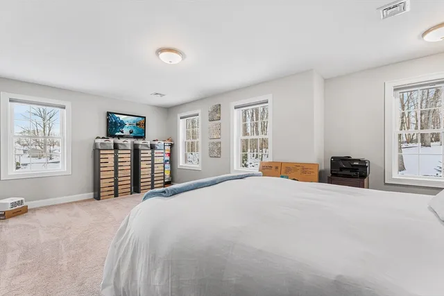 a large bed sitting in a spacious bedroom next to a window and a flat screen tv