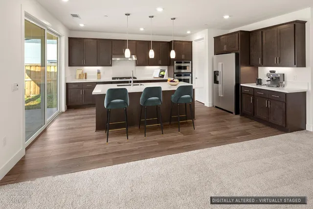 a kitchen with stainless steel appliances kitchen island granite countertop a refrigerator a stove a sink a dining table and chairs