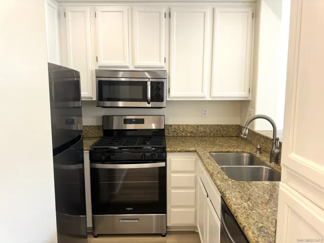 a kitchen with granite countertop a stove sink and microwave