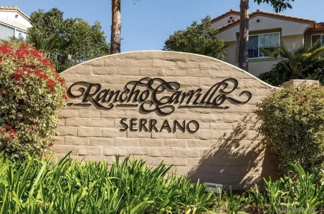 a view of sign board with buildings and trees