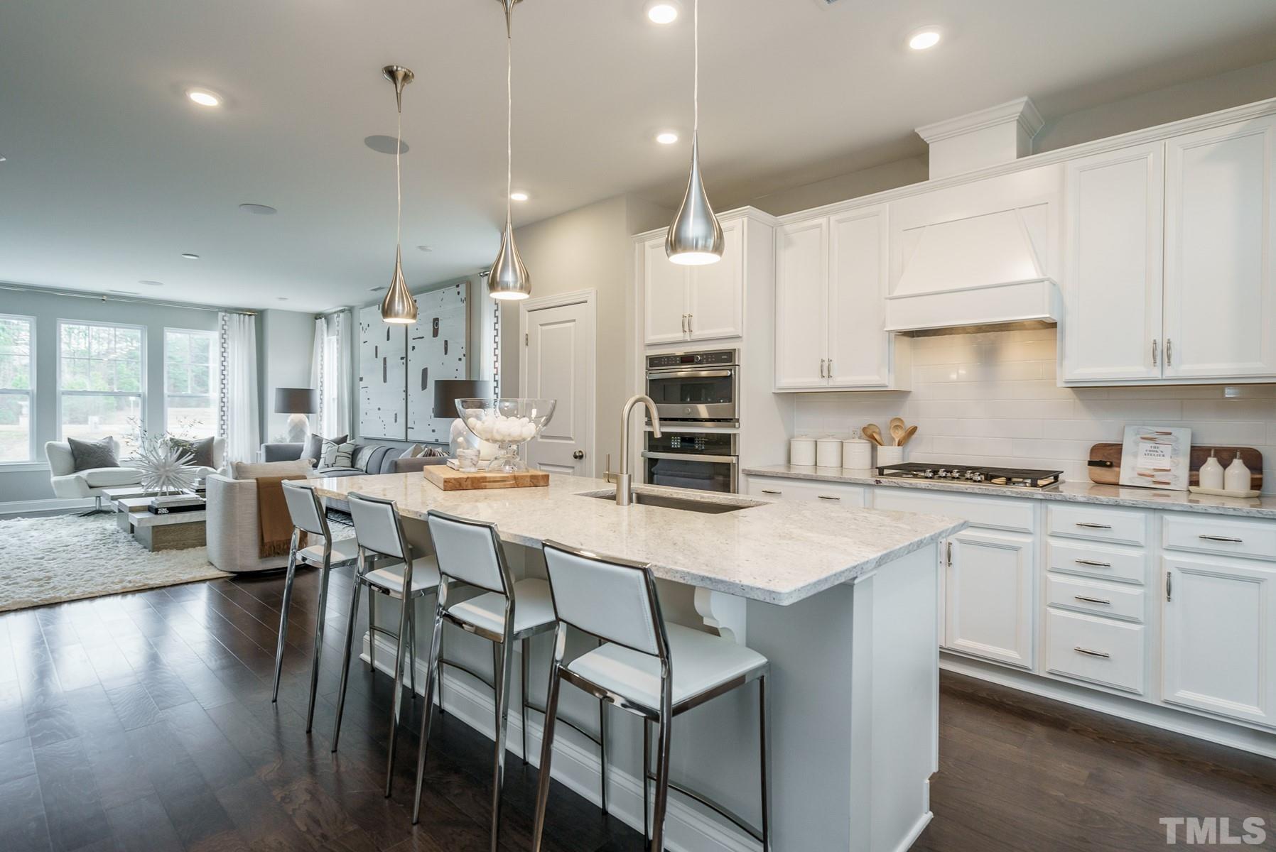 2225 Kettle Falls Station, Unit 392 Apex, NC 27502 - Photo 29 of 52 a kitchen with stainless steel appliances kitchen island granite countertop a table chairs sink and cabinets