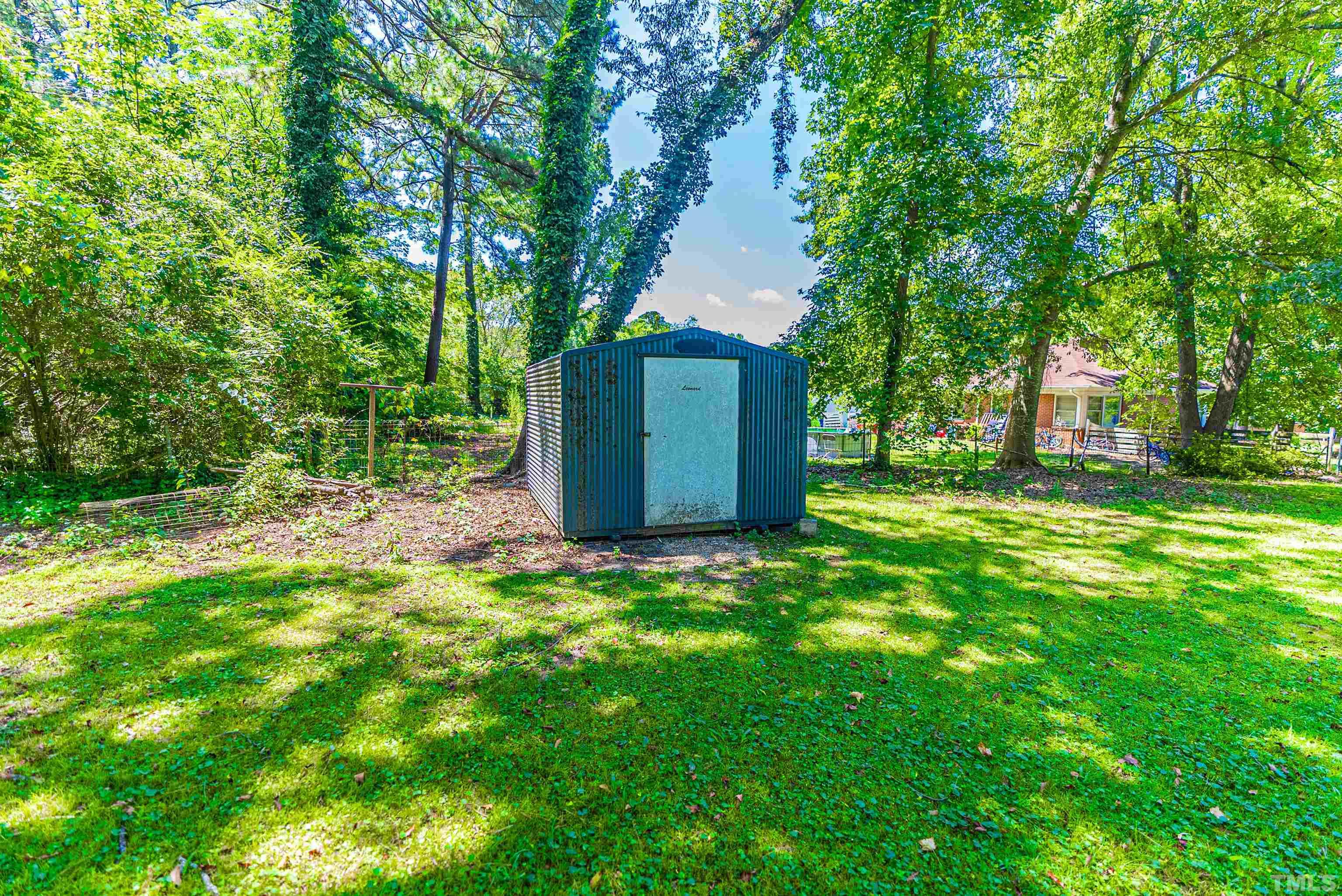 457 Rose Lane Raleigh, NC 27610 - Photo 16 of 26 a backyard of a house with large trees and outdoor seating